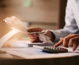 closeup-economist-using-calculator-while-going-through-bills-taxes-office 1
