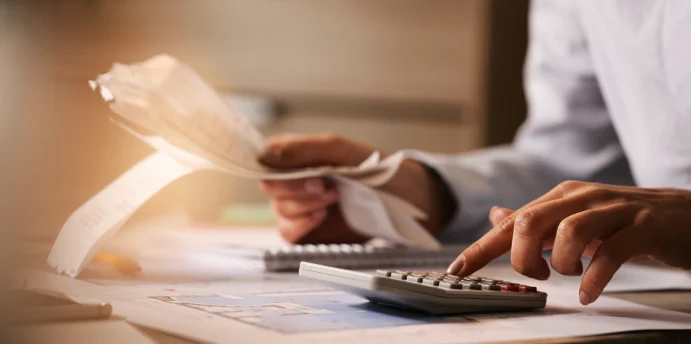 closeup-economist-using-calculator-while-going-through-bills-taxes-office 1