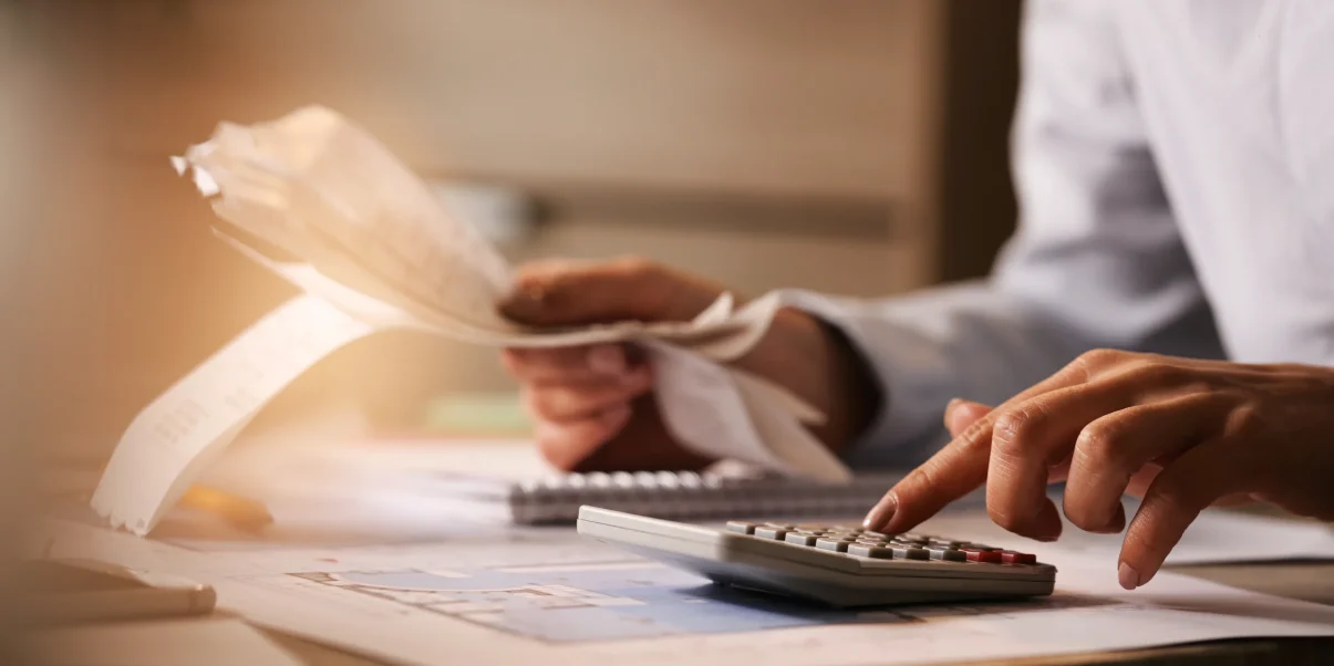 closeup-economist-using-calculator-while-going-through-bills-taxes-office 1